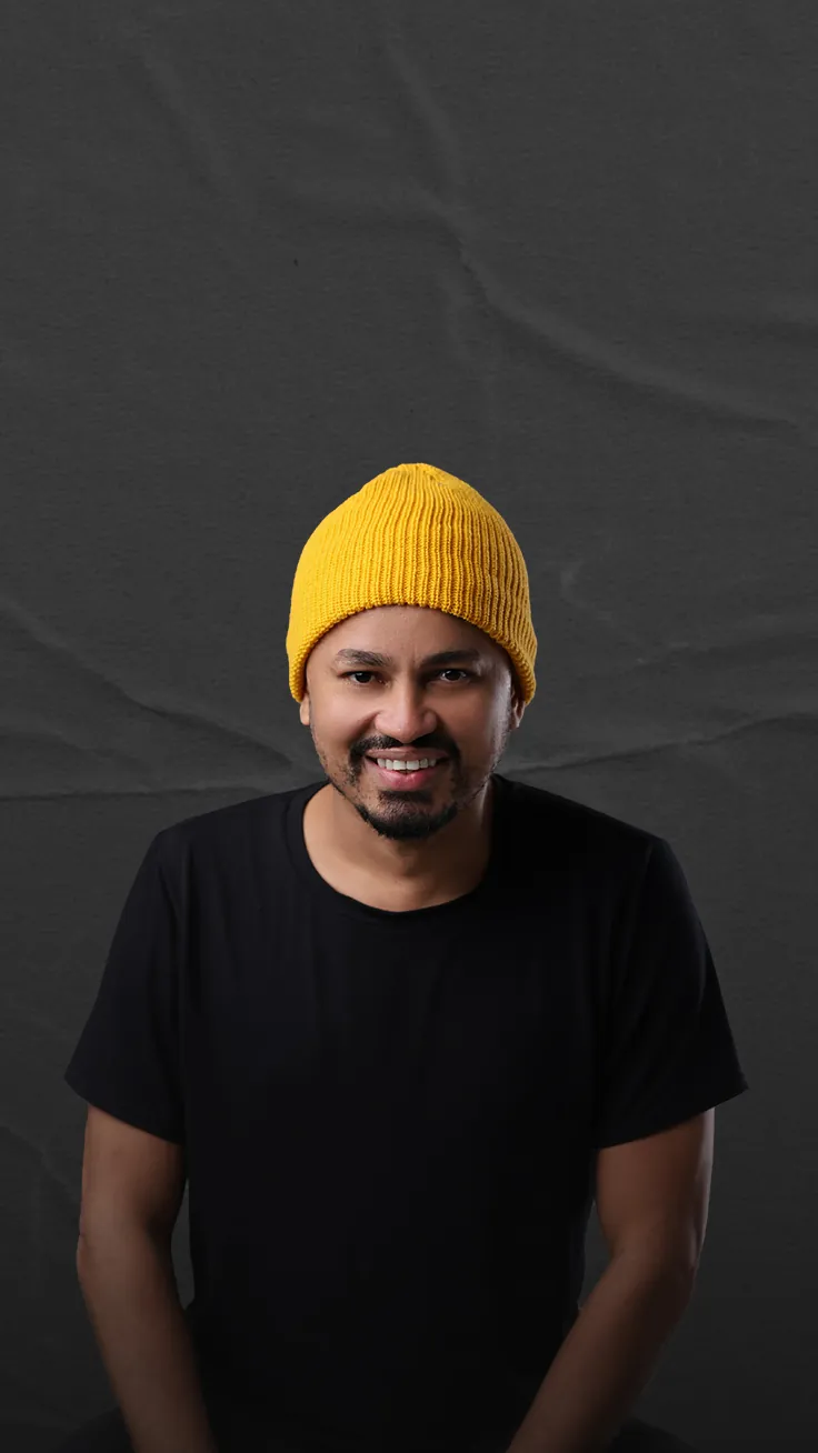 Júnior sorrindo, de gorro amarelo e camiseta preta